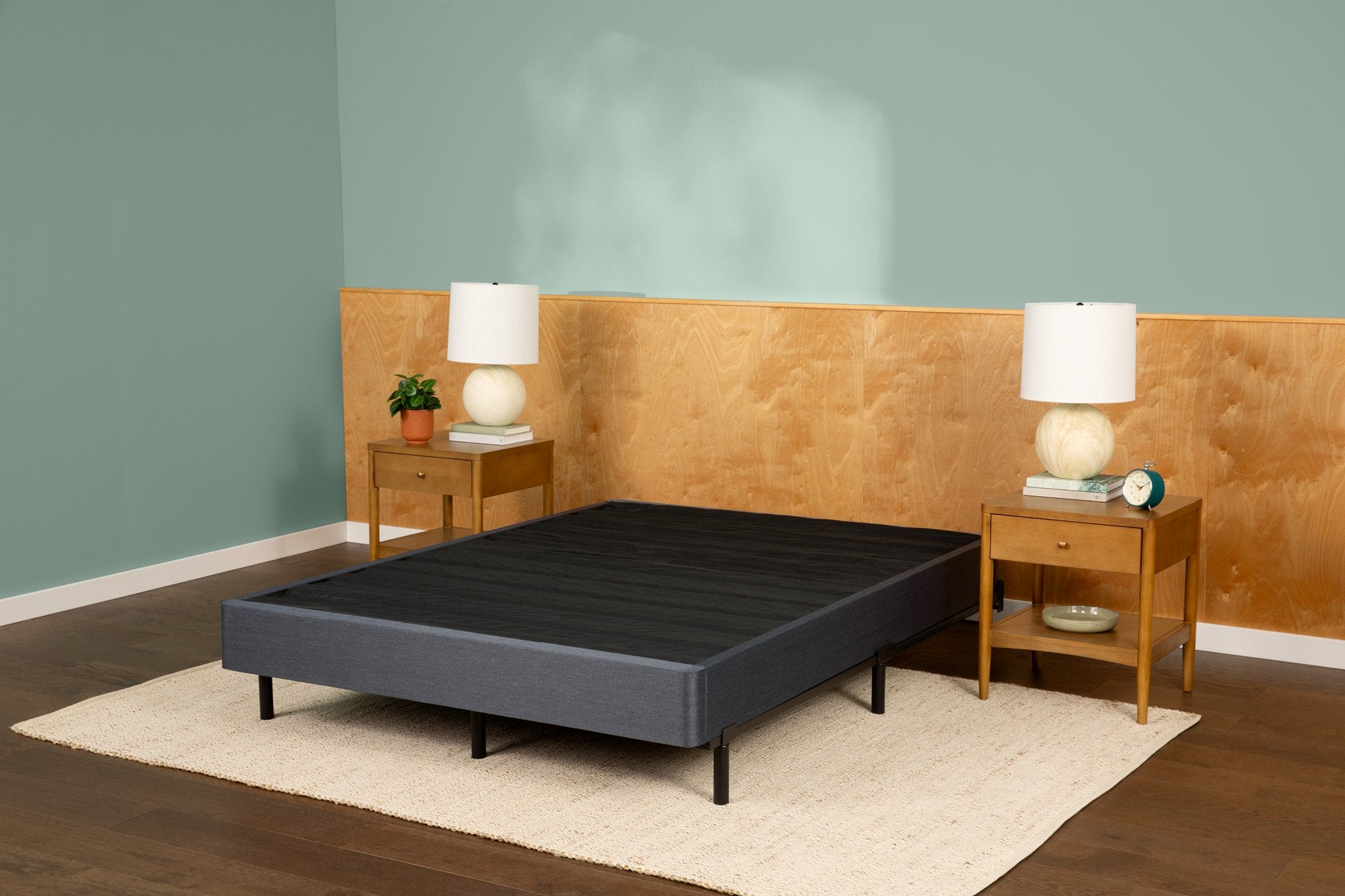 Tuft and Needle bed frame placed on a beige rug in between two end tables