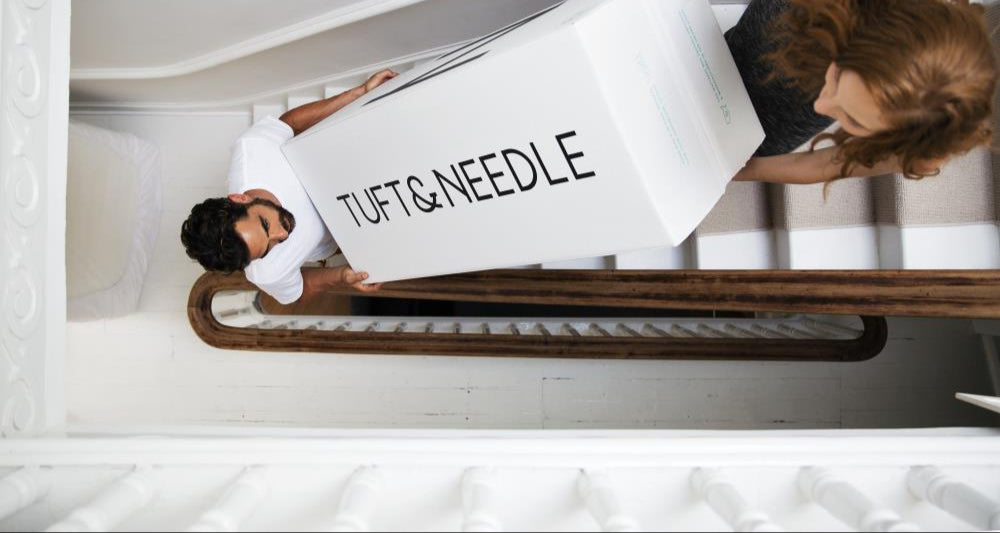 A couple carries a T&N package delivery up the stairs 