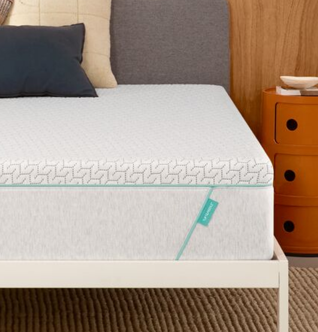 Tuft & Needle Original Hybrid mattress on a white bed frame next to an orange nightstand.