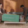 Couple unboxing a Tuft & Needle mattress and unrolling it on to their bed frame